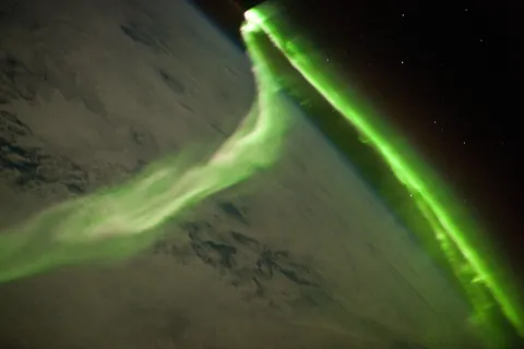 NASA astronaut photograph of green southern aurora following Earth’s curved horizon, seen from the International Space Station.